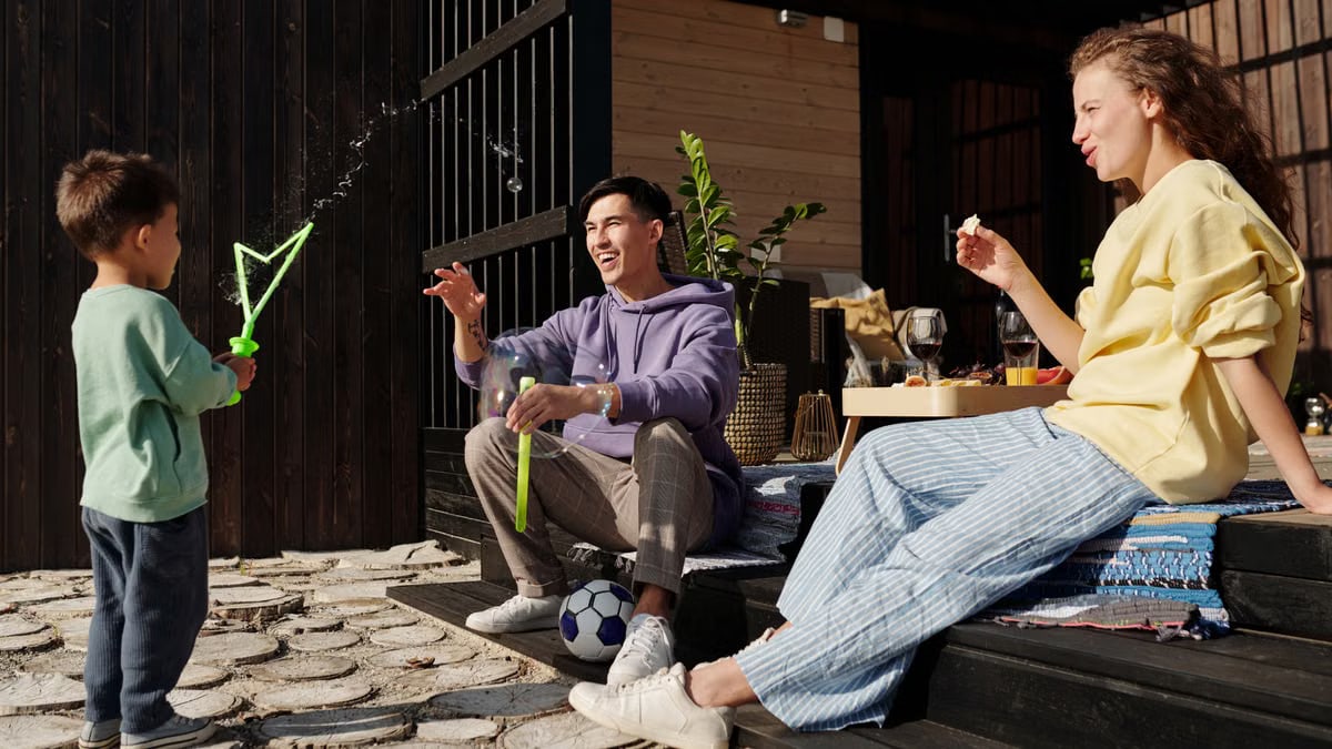 A family spends quality time playing with bubbles outside on a sunny day.